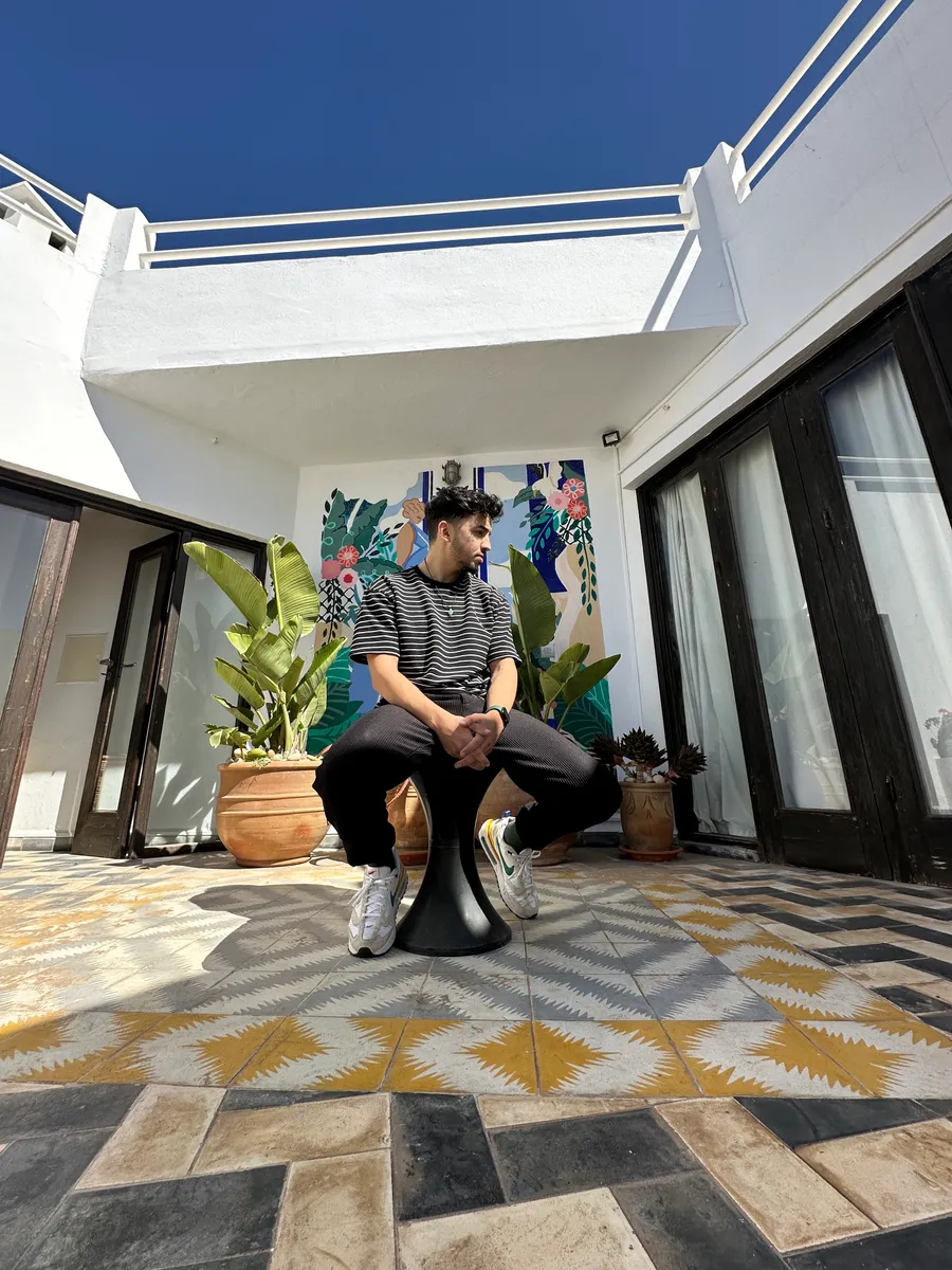 Nourdine seated on a stool in a sunlit tiled courtyard